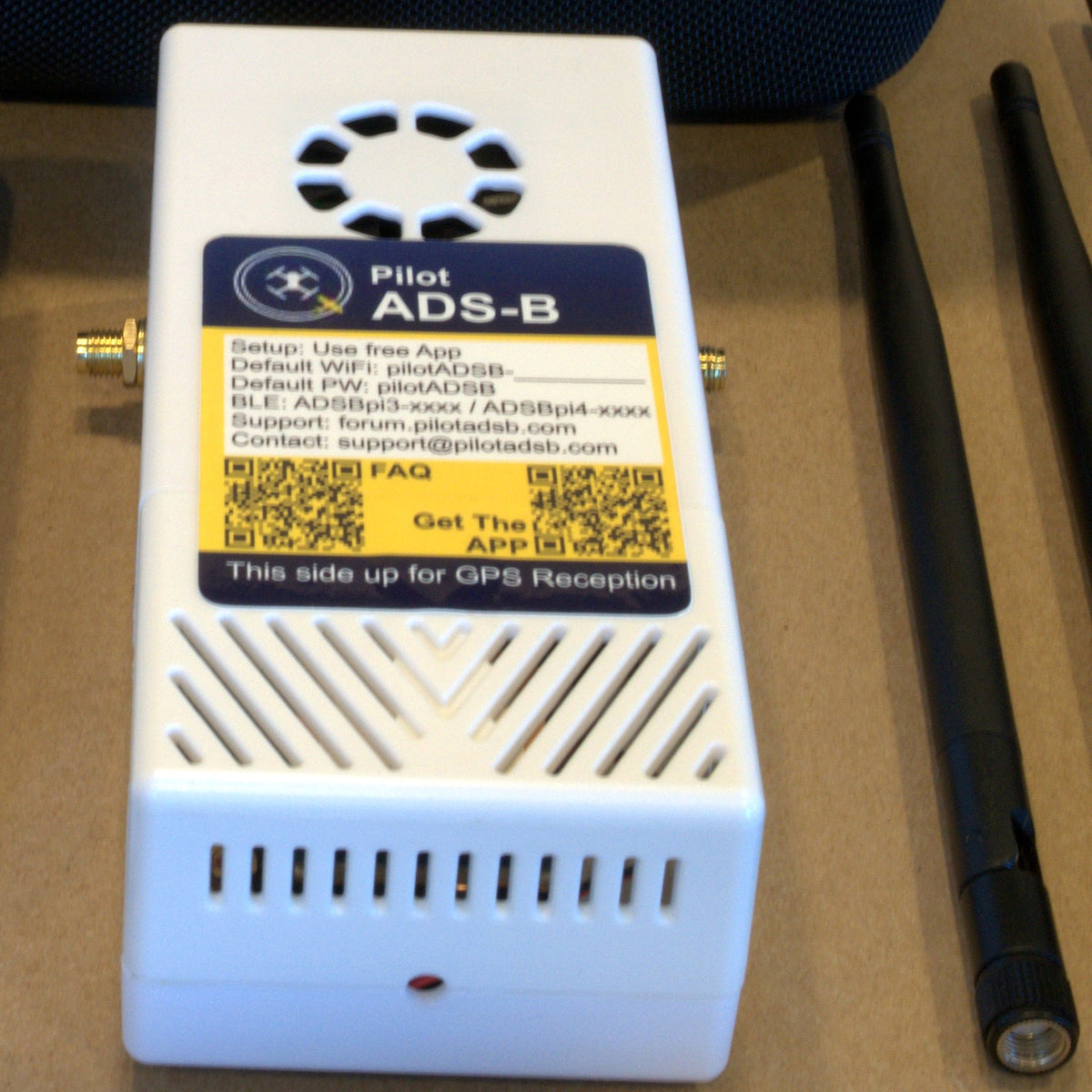 Close-up of the pilotADSB Remote ID receiver with its setup label and QR codes